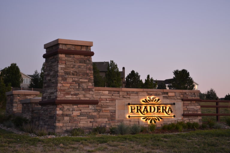 Pradera halo-lit community identity mounted on a stone entrance monument
